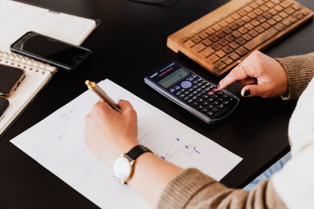 Birou de lucru al unui creator independent, cu schițe, carnet de notițe și calculator pentru stabilirea tarifelor